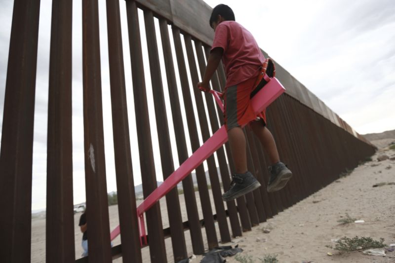 CORRECTS THE FIRST NAME OF THE PROFESSOR TO RONALD, NOT RONALDO AND THE LAST NAME OF THE PHOTOGRAPHER TO CHAVEZ, NOT TORRES - A child plays seesaw installed between the border fence that divides Mexico from the United States in Ciudad de Juarez, Mexico, Sunday, July 28, 2019. The seesaw was designed by Ronald Rael, a professor of architecture in California. (AP Photo/Christian Chavez)